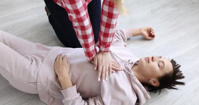 Person doing cardiopulmonary resuscitation to unconscious young woman