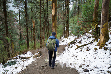 Fototapeta premium A Man hiking down rocky trail steps among natural landscape of snow mountain park