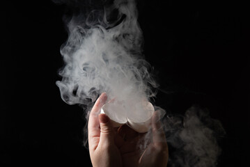 Smoke comes out of a broken egg in female hands.
