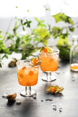 Orange healthy col beverage cocktail decorated with physalis berry. Alcoholic food photo bar drink in a garden on table.