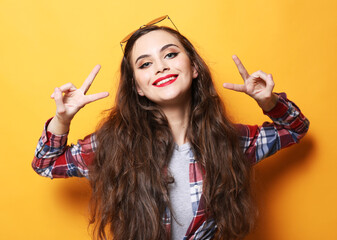 Obraz premium Portrait of smiling young curly woman showing victory sign near face