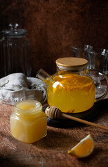 A teapot of tea with sea buckthorn, lemon and honey. The background is dark, vertical orientation.