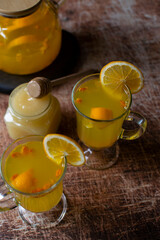 Two mugs with sea buckthorn tea on a wooden table. Top view, dark background, vertical orientation.