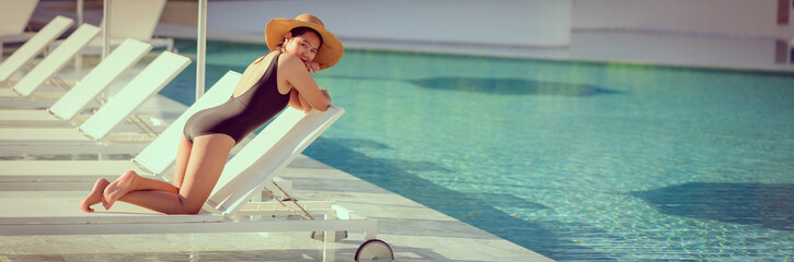 Young Asian woman with hat relaxing beside the pool at luxury hotel. travel and summer concept background.,cover banner concept vocation summer