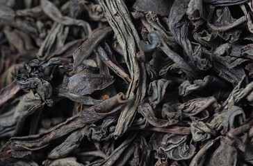 Dried black tea leaves as background.