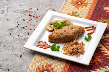 Cutlet with buckwheat with mushrooms on white plate