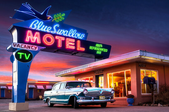 Tucumcari, NM - USA - March 16 2022: Historic Blue Swallow Motel on Route 66 with Neon and Classic Car at Sunset.