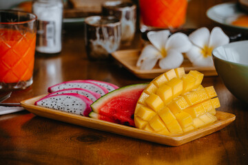 The fruit in the tray has dragon fruit, mango, watermelon and fruit juices set in the background.