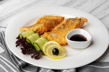 Fried fish fillet and vegetables on white plate