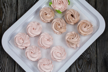 Homemade marshmallows of different shapes and colors. Zephyr flowers. On pine boards.