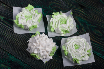 Homemade marshmallows of different shapes and colors. Zephyr flowers. On pine boards.