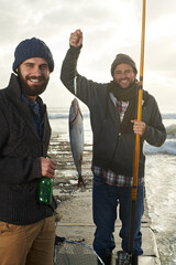 Were eating fish tonight. Shot of two young men fishing off a pier with a fish on a line.