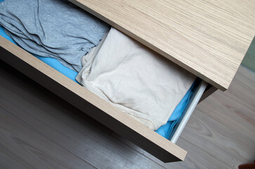 Open wooden dresser drawer with clothes