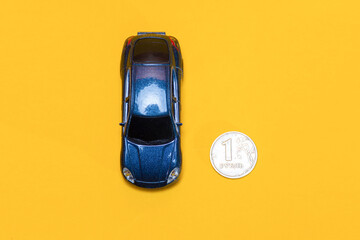Ivanovo, Russia - 03.03.2022:miniature car with one Russian ruble on yellow background with place...