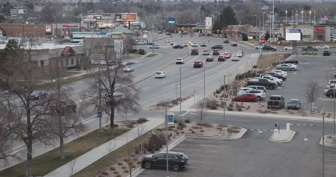 City traffic cars urban city road Provo Utah fast motion. Vehicles driving road intersection late afternoon. Buildings, businesses along transportation route. View from above high angle.