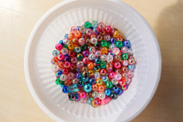 Naklejka na ściany i meble Beads of various colors are placed in a white plastic glass.