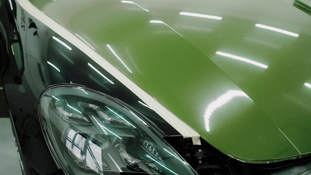 Beautiful example of vinyl car wrapping in green color. Modern car in black and green colours. Result of car wrapping. Shiny green car hood. High quality 4k footage