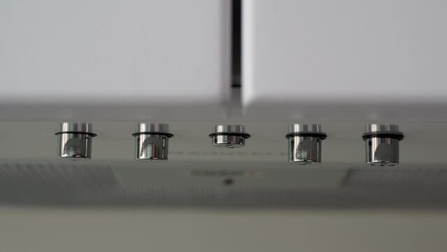 The finger presses the metal button on the cooker hood to turn it on and off. Household appliances in the kitchen. House.