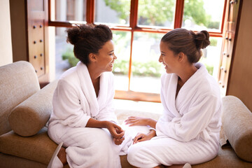 Chilling at the spa. Shot of two friends in bathrobes talking an laughing at a spa.