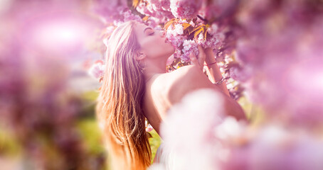 Young beautiful sexy carefree woman posing on the spring background. Summer model holding flowers...