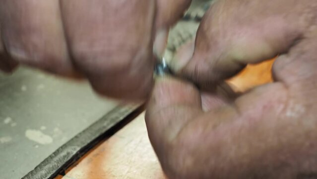 Man positions the chain saw link of a chainsaw for riveting. Close-up shot with selective focus