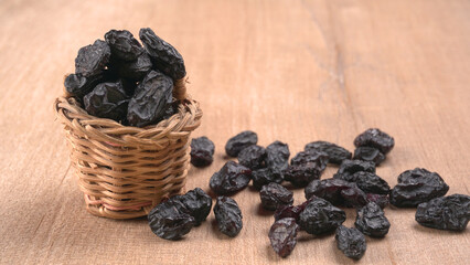 black raisins in a bowl on a wooden table. black raisins in a spoon