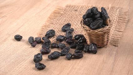 black raisins in a bowl on a wooden table. black raisins in a spoon
