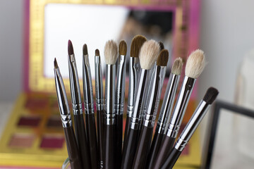 Makeup brushes against the background of shadows and sculptures. Make-up artist's desk