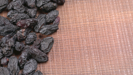 black raisins in a bowl on a wooden table. black raisins in a spoon