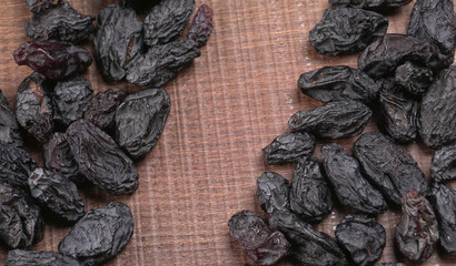 black raisins in a bowl on a wooden table. black raisins in a spoon