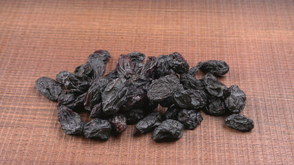 black raisins in a bowl on a wooden table. black raisins in a spoon