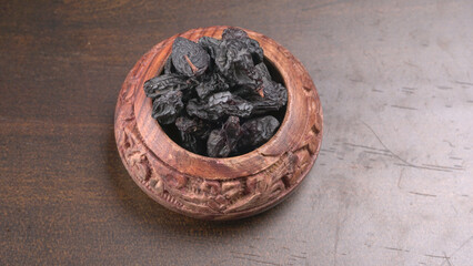 black raisins in a bowl on a wooden table. black raisins in a spoon