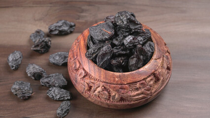 black raisins in a bowl on a wooden table. black raisins in a spoon