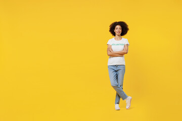 Fototapeta na wymiar Full body fun young woman of African American ethnicity wears white volunteer t-shirt hold hands crossed folded isolated on plain yellow background. Voluntary free work assistance help grace concept.