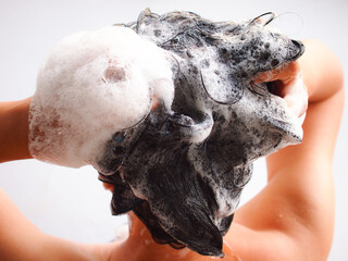 woman washing her hair with shampoo in bathroom.