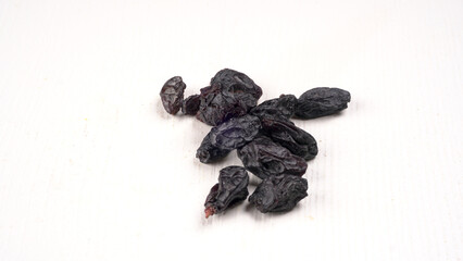 black raisins in a bowl on a wooden table. black raisins in a spoon