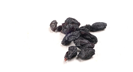 black raisins in a bowl on a wooden table. black raisins in a spoon