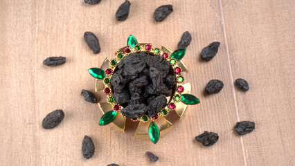 black raisins in a bowl on a wooden table. black raisins in a spoon