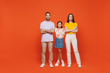 Fototapeta premium Full body young fun happy parents mom dad with child kid daughter teen girl in basic t-shirts hold hands crossed folded isolated on yellow background studio. Family day parenthood childhood concept