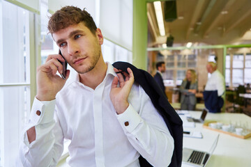 Start-up founder talking on the phone with his smartphone