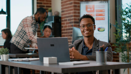 Portrait of male employee with disability smiling on camera, getting ready to work on financial presentation for business development. Young man planning data solution for growth. Handheld shot.