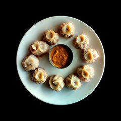 Steam-cooked momos with sauce, Nepalese Traditional Dish Momo. Steam momos on the black background.