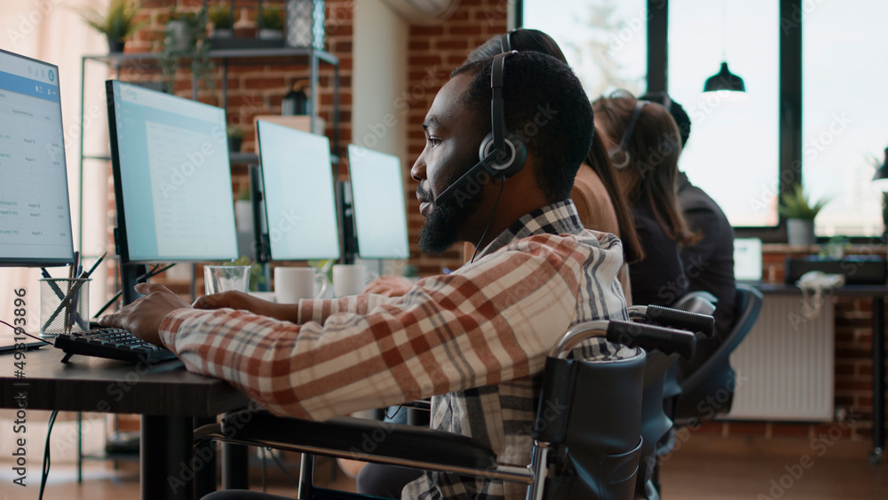 Poster office worker with handicap using headset to talk to clients at call center workstation. sales consu