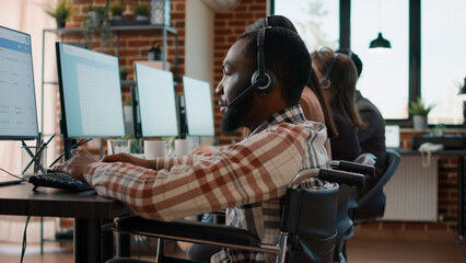 Office worker with handicap using headset to talk to clients at call center workstation. Sales consultant having telemarketing conversation with people on helpline at customer service.