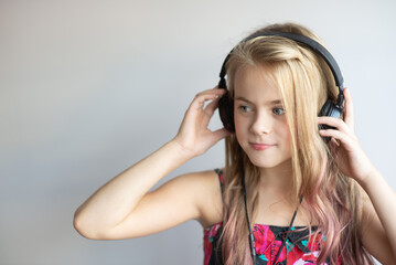 Naklejka premium Photo portrait of smiling little girl listening to music with black earphones 
