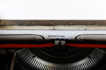 The German word Bewerbung written in red on an old mechanical typewriter Deuscher Text: Application