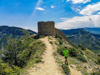 A boy against the background of the Gunib fortress. A protective wall. Russia, Dagestan. June 2021