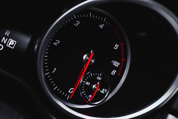 Car tachometer with glowing red indicators close-up view, of luxury dashboard in sport car