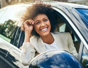 Today will be a good day. Shot of a cheerful young businesswoman driving in a car to work with her...