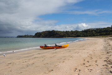 Picturesque landscape with orange kayak boat at white sand beach, Te Haruhi Bay at Shakespear Regional Park, New Zealand.